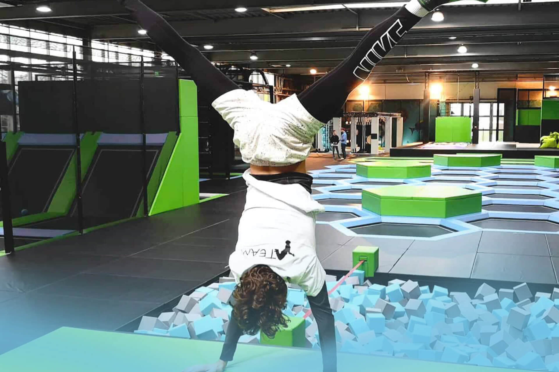 Sportlicher Besucher zeigt einen Handstand über der Schaumstoffgrube im SkyandSand Trampolinpark Würzburg.